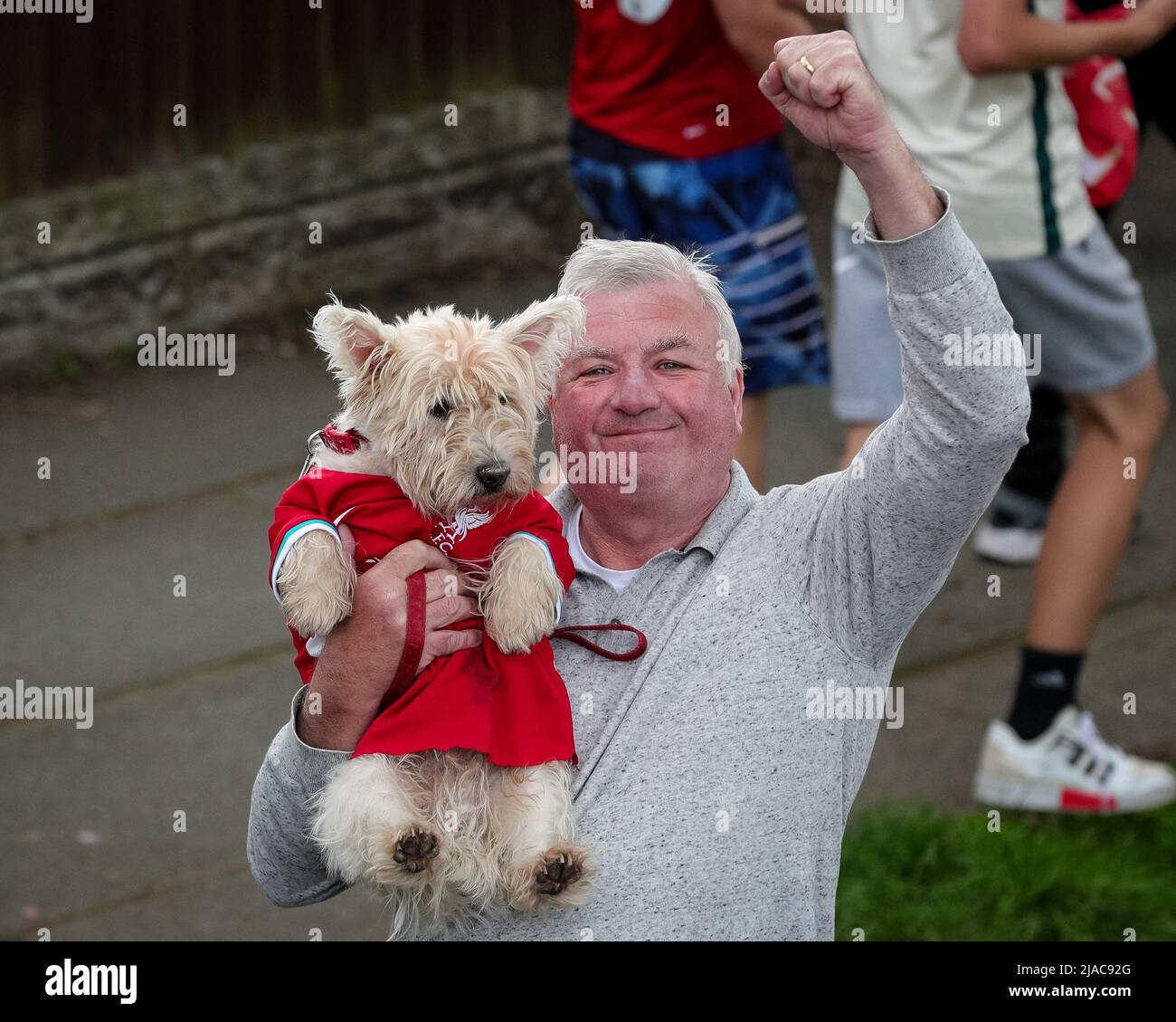 Un sostenitore di Liverpool e il suo cane incoraggiano la squadra del Liverpool FC a festeggiare durante la sfilata di autobus scoperto attraverso la città dopo aver vinto sia la Carabao Cup che la fa Cup nella stagione 2021/22 Foto Stock