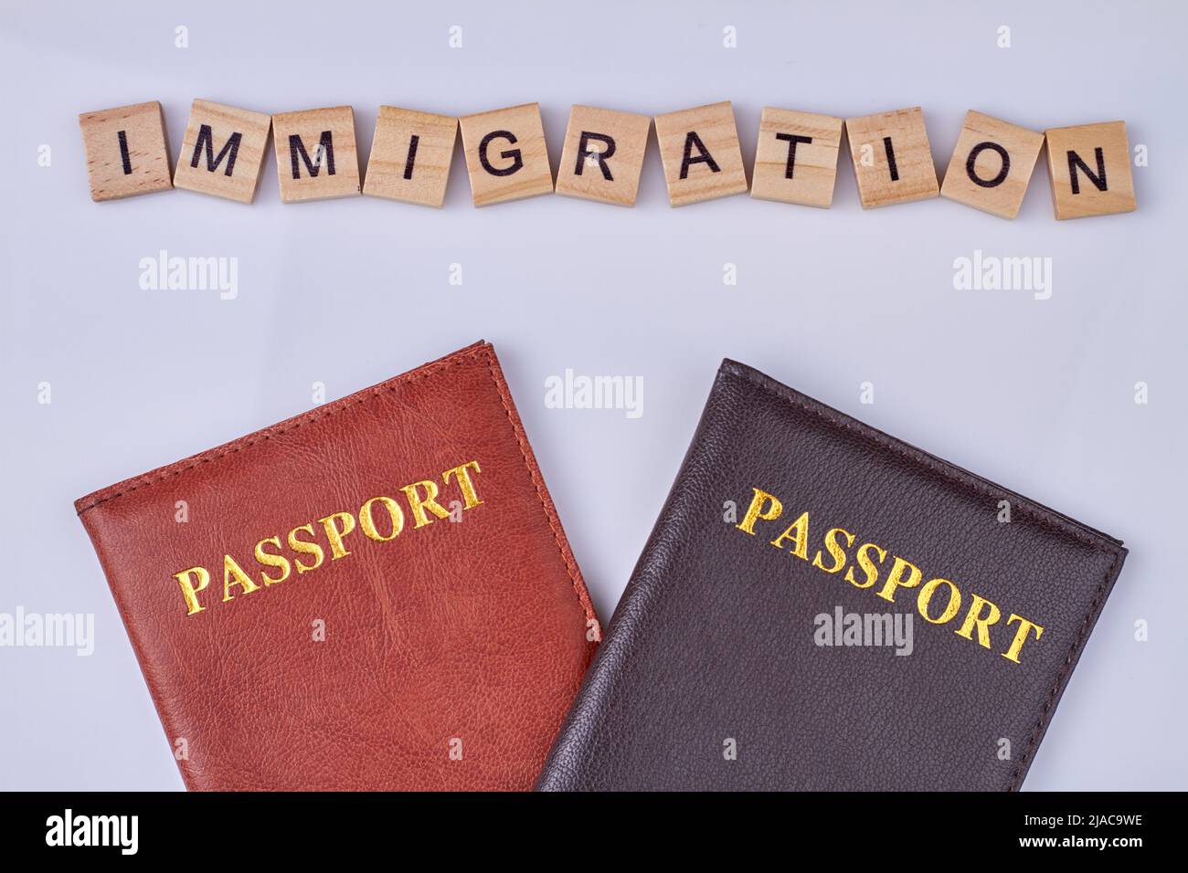 Cubetti di legno con iscrizione IMMIGRAZIONE e due passaporti. Composizione piatta su sfondo chiaro. Foto Stock