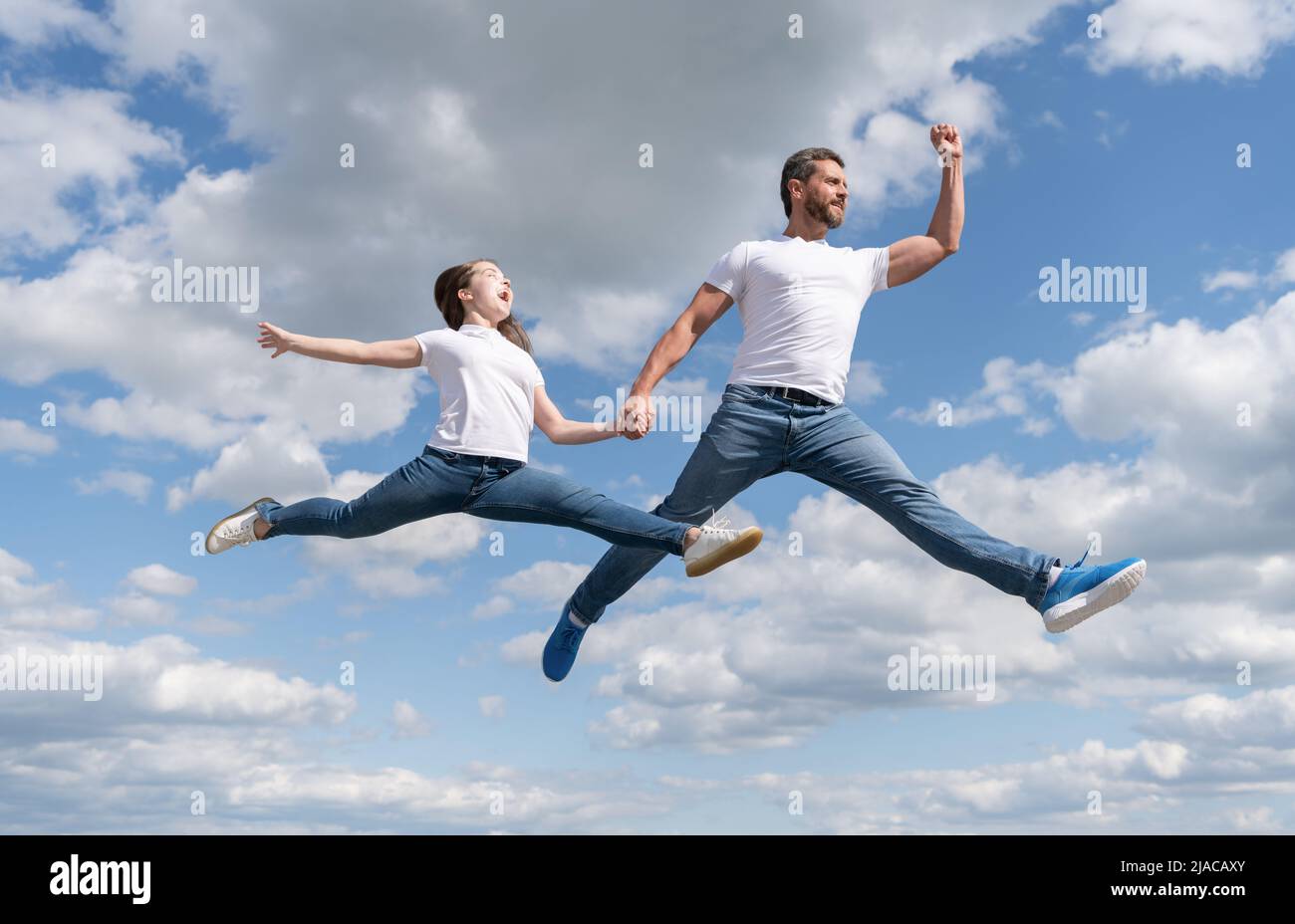 felice famiglia di padre e figlia saltare in cielo Foto Stock