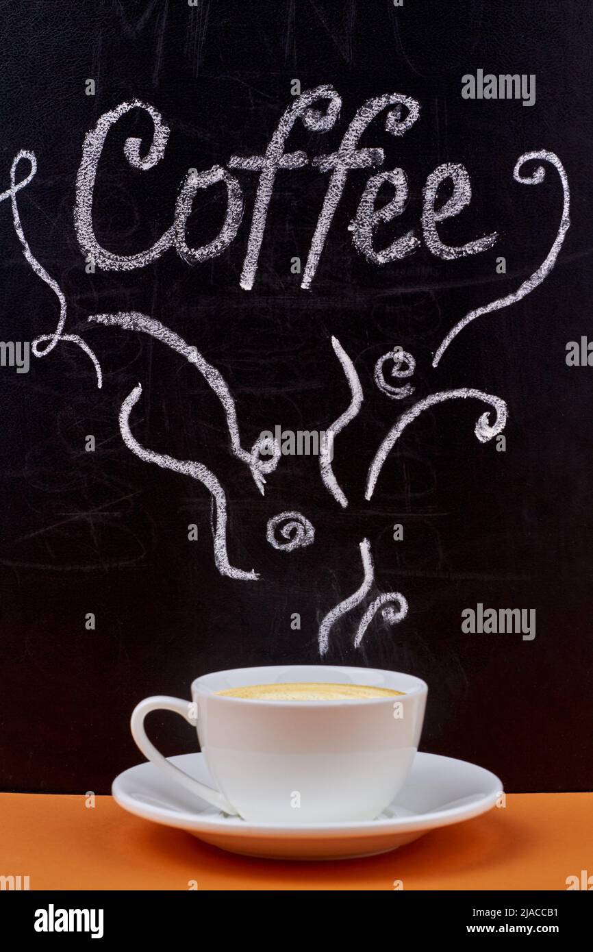 Caffè scritto a mano sulla lavagna e tazza di cappuccino su tavola di legno. Gustosa bevanda calda. Foto Stock