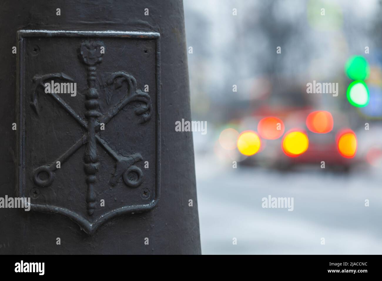 Cappotto di armi della città di San Pietroburgo, elemento decorativo su una luce di strada nera nel quartiere centrale, luci auto sfocate sono su uno sfondo Foto Stock