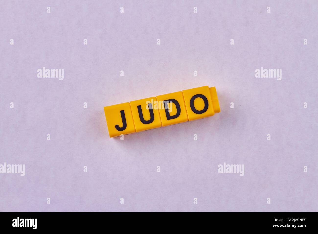 La parola judo scritta su cubi gialli sullo sfondo a colori. Tipo di sport. Foto Stock