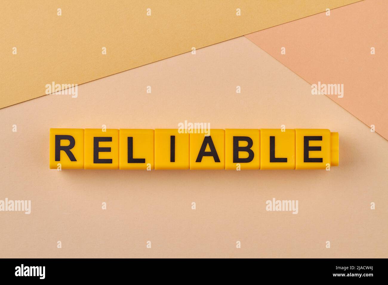 La parola affidabile scritta su cubi gialli primo piano. Qualità o prestazioni sempre buone. In grado di essere affidabile. Foto Stock