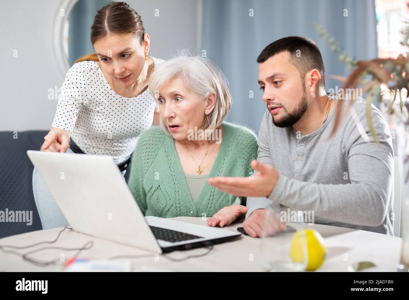Coppia giovane che aiuta la donna anziana ad usare il laptop Foto Stock