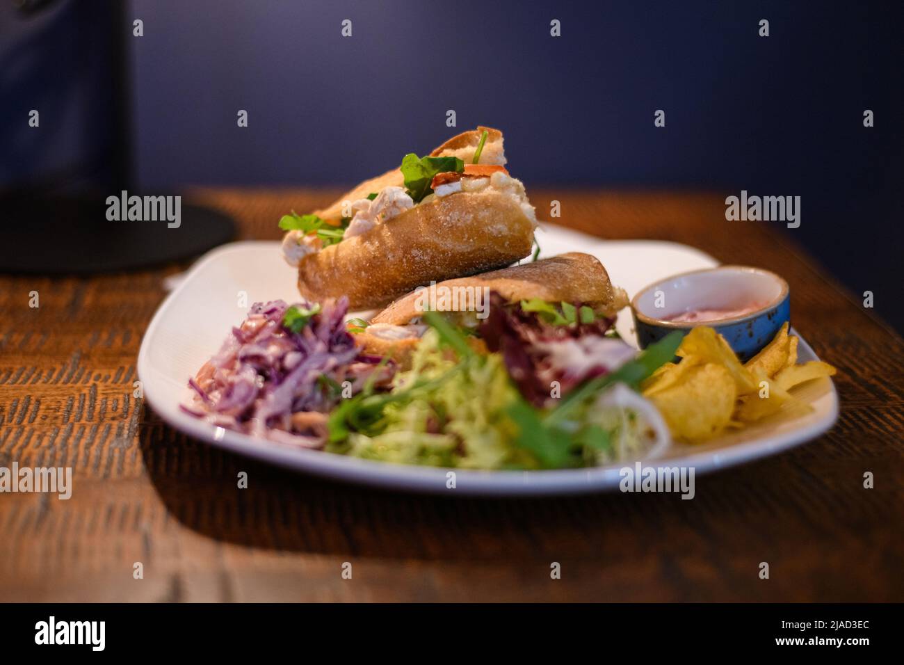 Primo piano di panini con pollo, brie e insalata con insalata di coleslaw, insalata verde e patatine Foto Stock