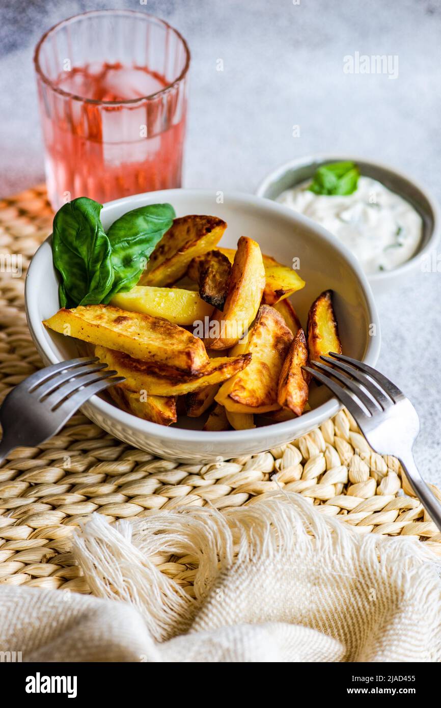 Vista dall'alto di una ciotola di patate arrosto con salsa panna acida e una bevanda rosa Foto Stock