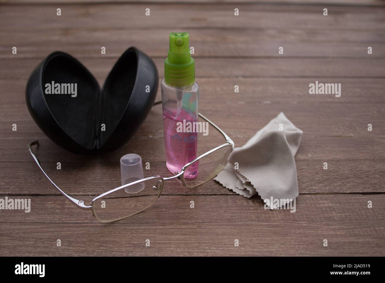 Immagine di un paio di occhiali con il loro caso, un cerotto e una bottiglia di spray. Fare riferimento a come pulire gli occhiali Foto Stock