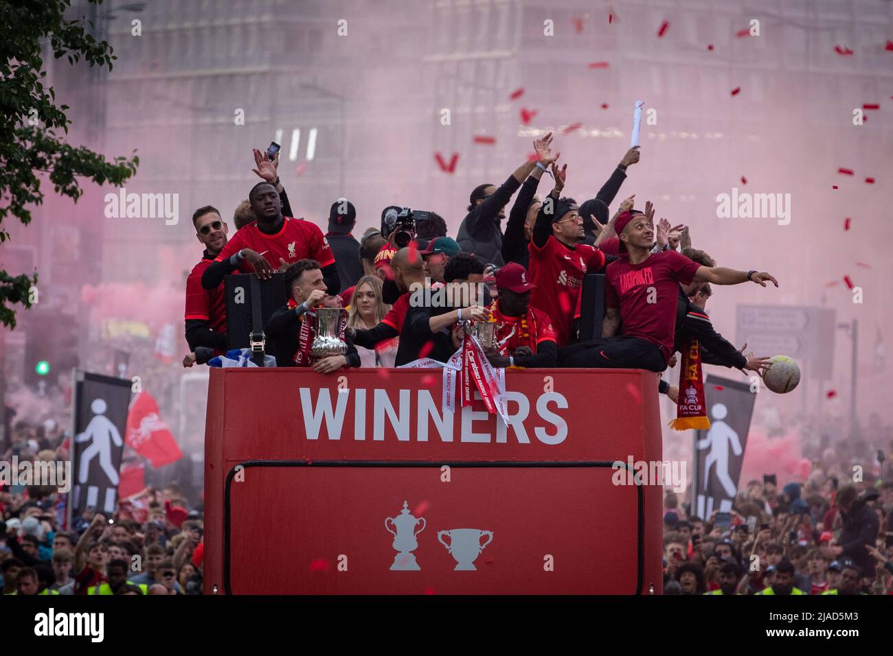 I tifosi lanciano un calcio fino alla squadra del Liverpool FC durante la sfilata di autobus scoperto attraverso la città dopo aver vinto sia la Carabao Cup che la fa Cup nella stagione 2021/22 Foto Stock