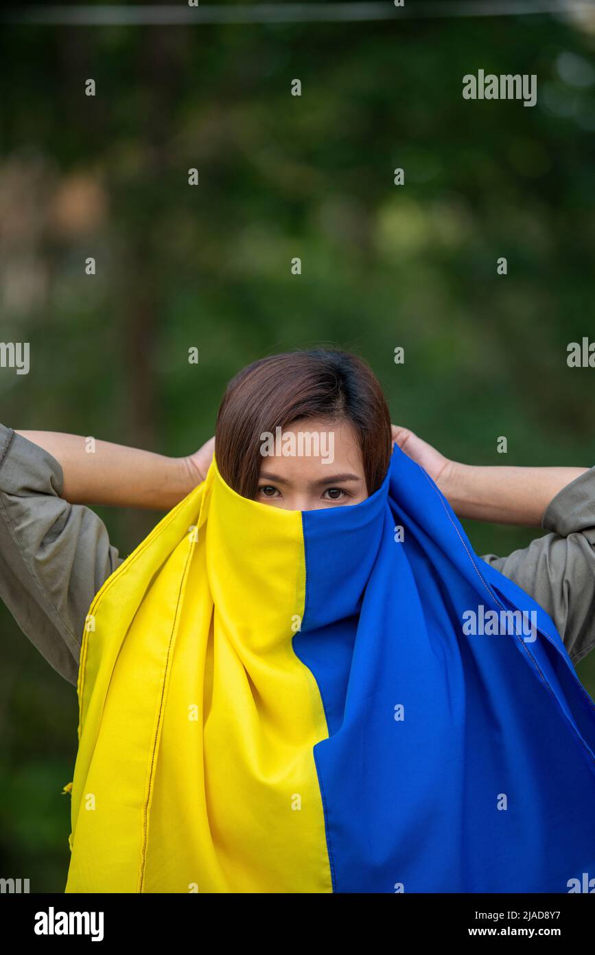 Ritratto di una donna che detiene una bandiera Ucraina davanti al suo volto Foto Stock