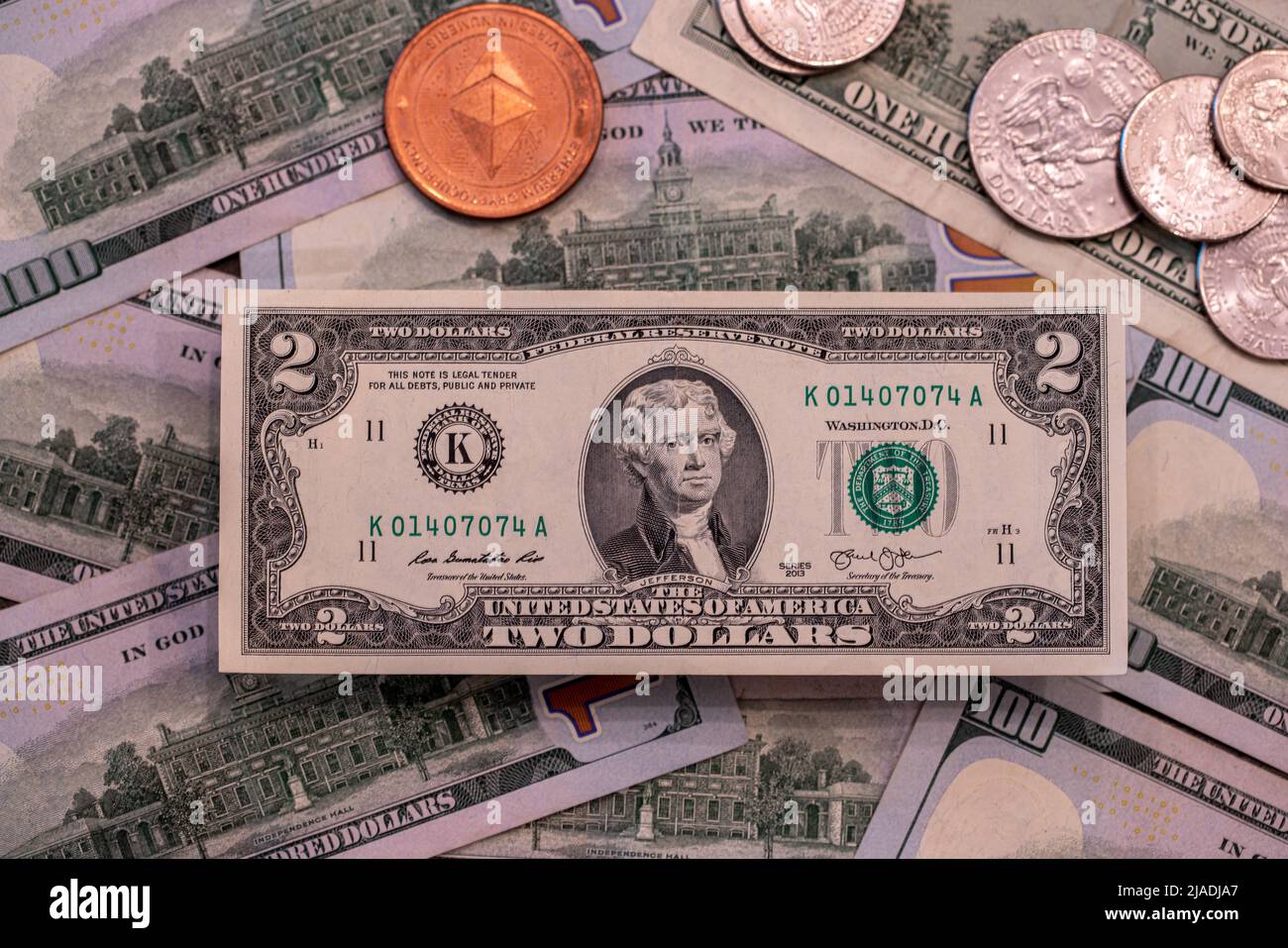 Rara banconota da due dollari in più di 100 dollari accanto alla moneta Ethereum. Il commercio di criptovaluta e l'estrazione mineraria negli Stati Uniti d'America Foto Stock