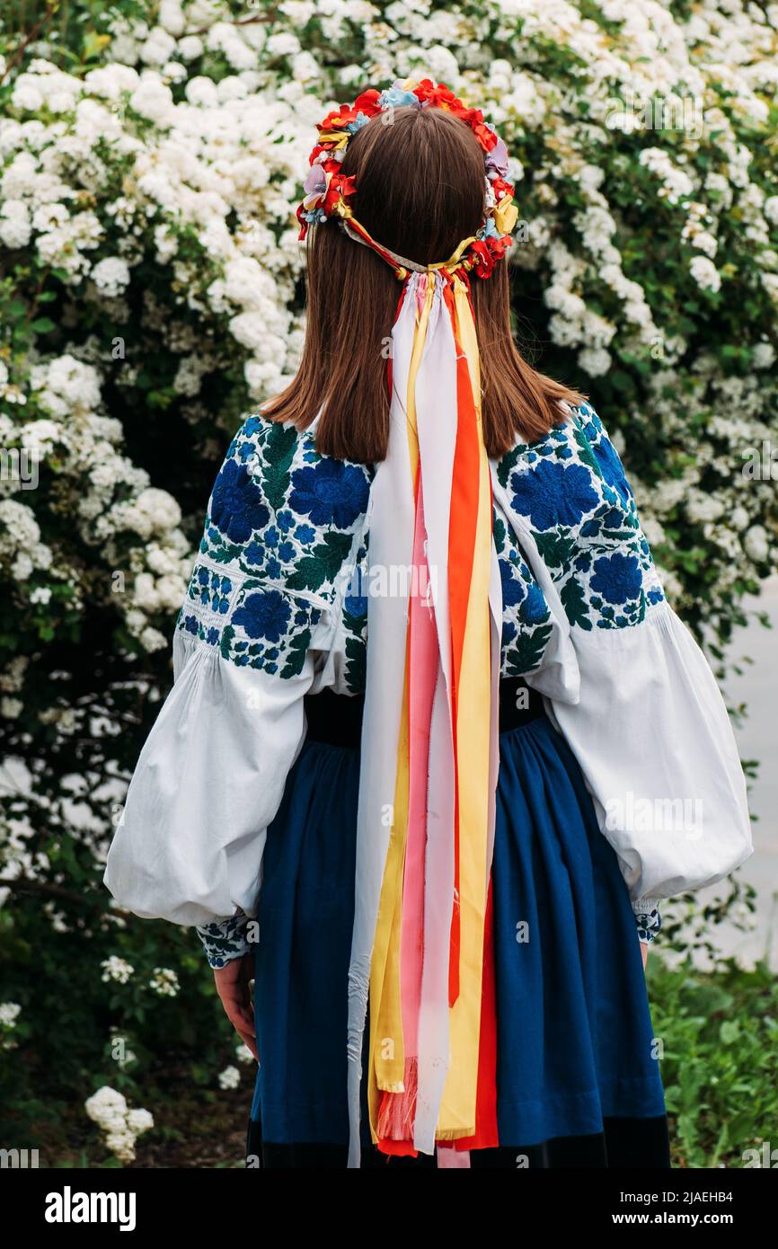La ragazza si alza con la schiena in abiti nazionali ucraini e una corona con nastri sulla testa. Foto Stock