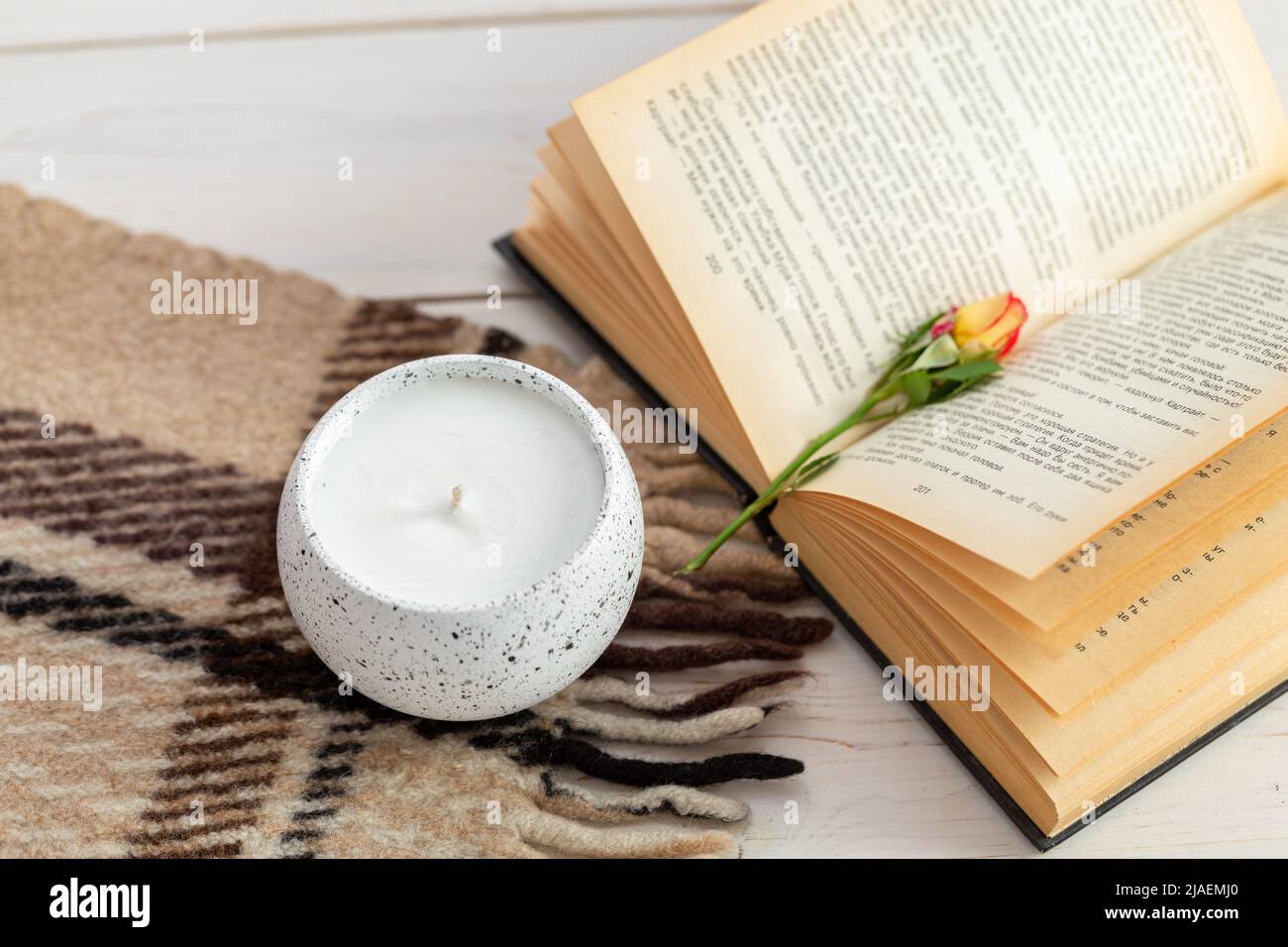 Bella composizione con una candela, una rosa, un libro e una plaid su un  tavolo di legno. Zen e relax concetto. Arredamento interno accogliente Foto  stock - Alamy
