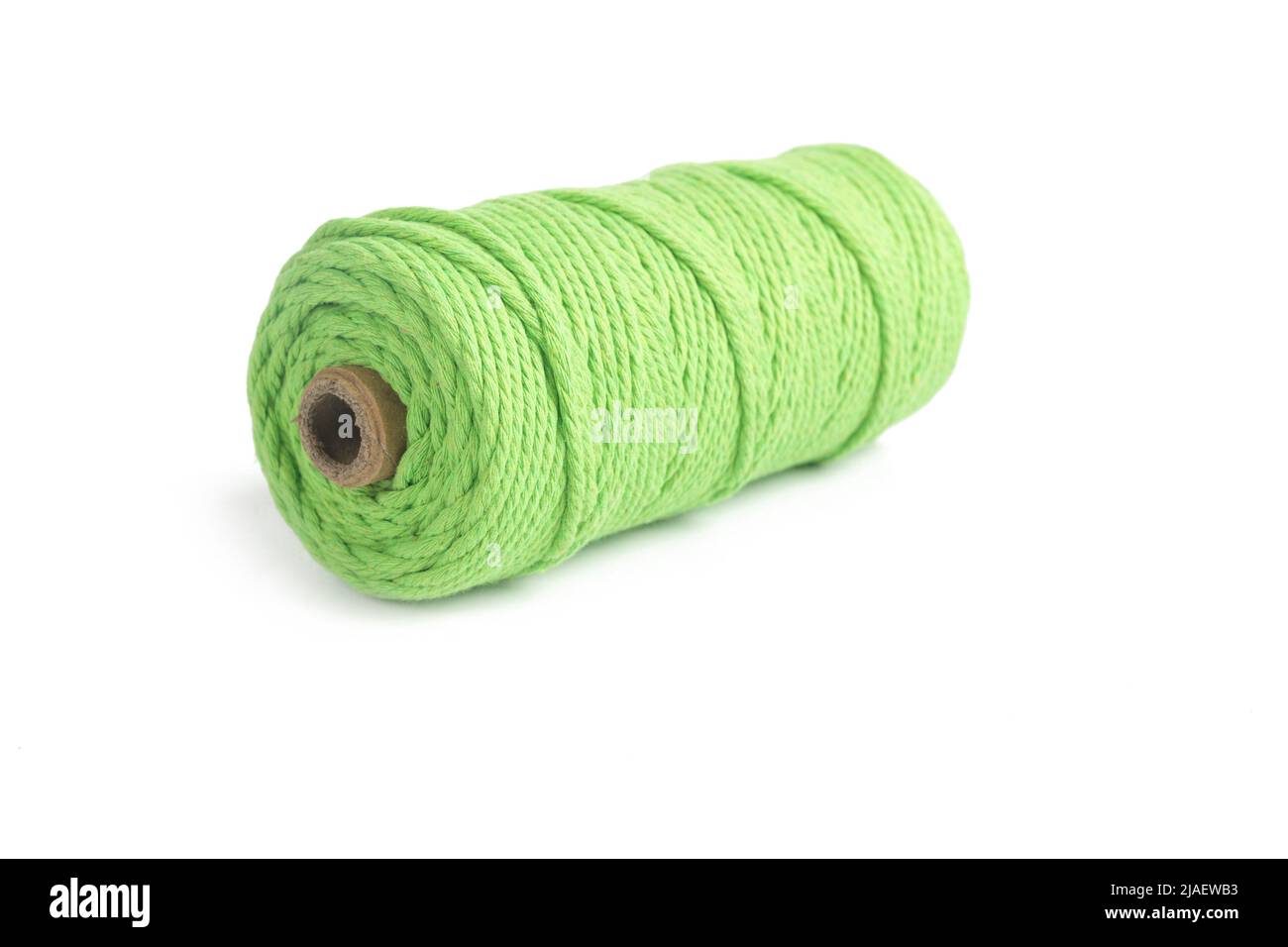 Matassa di colore verde a filo singolo corda di cotone per macrama su bianco. Da utilizzare per il fai-da-te. Primo piano bobina tessile Foto Stock