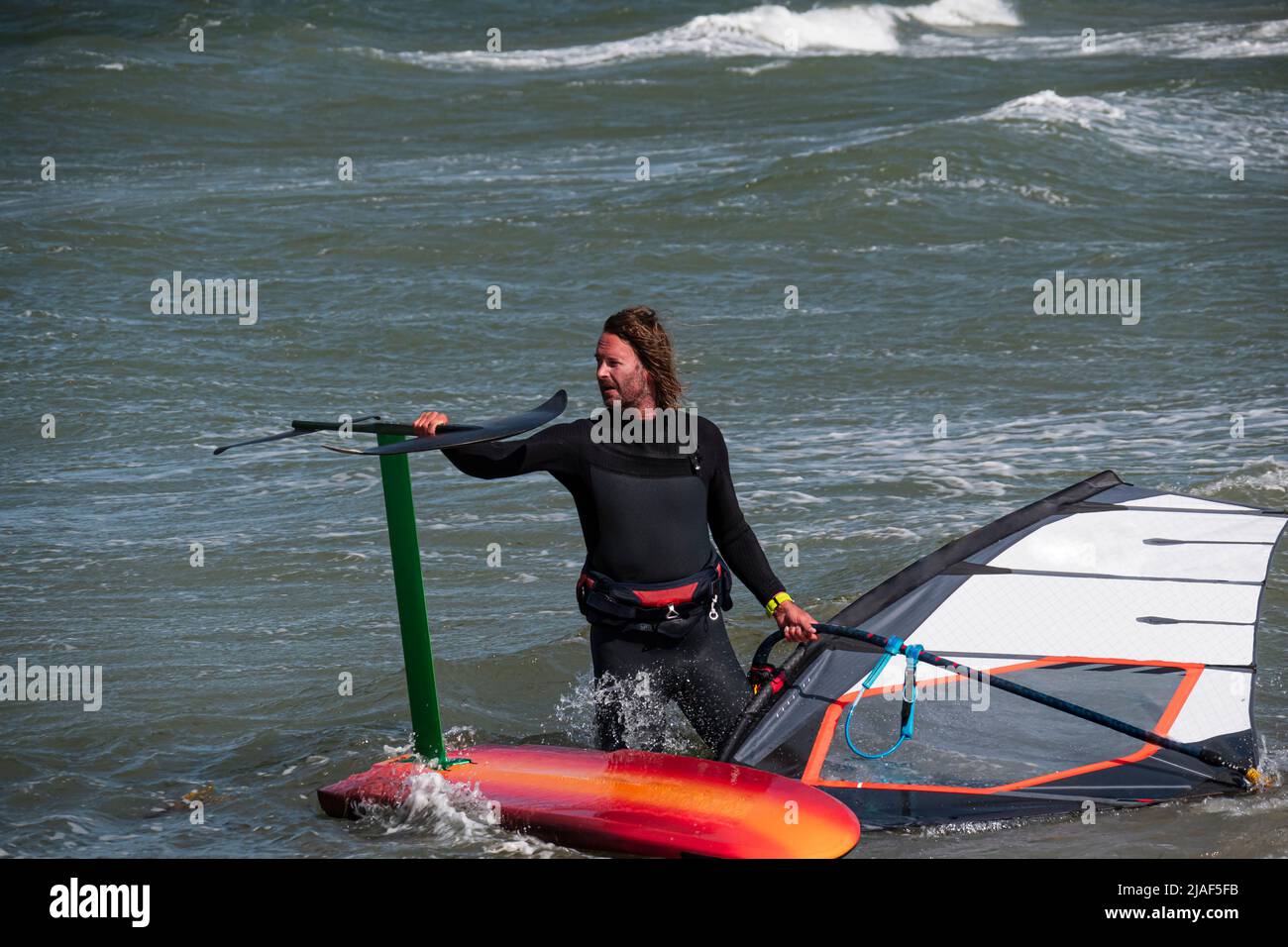 Il surfer di foglio di vento va nel mare con la sua scheda di aliscafo Foto Stock
