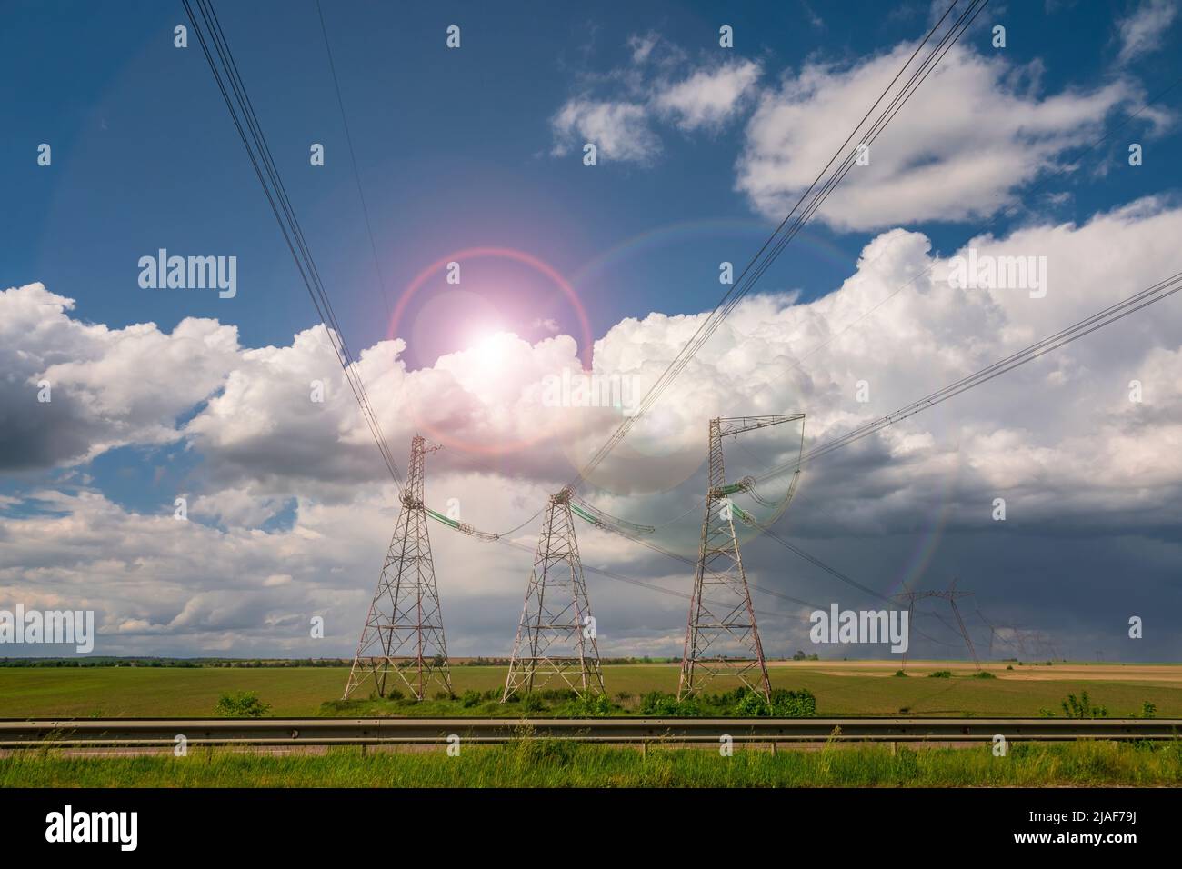 Linee di alimentazione contro il cielo blu con nuvole e sole flare. Energia in Ucraina Foto Stock