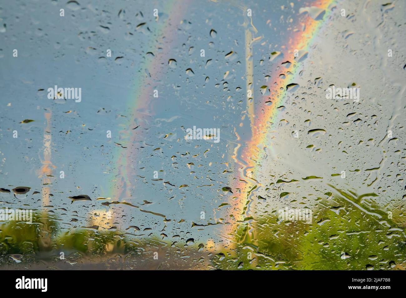 Rogge e arcobaleno sul vetro del vento dell'auto. Guida nel concetto di giorno piovoso. Background creativo Foto Stock