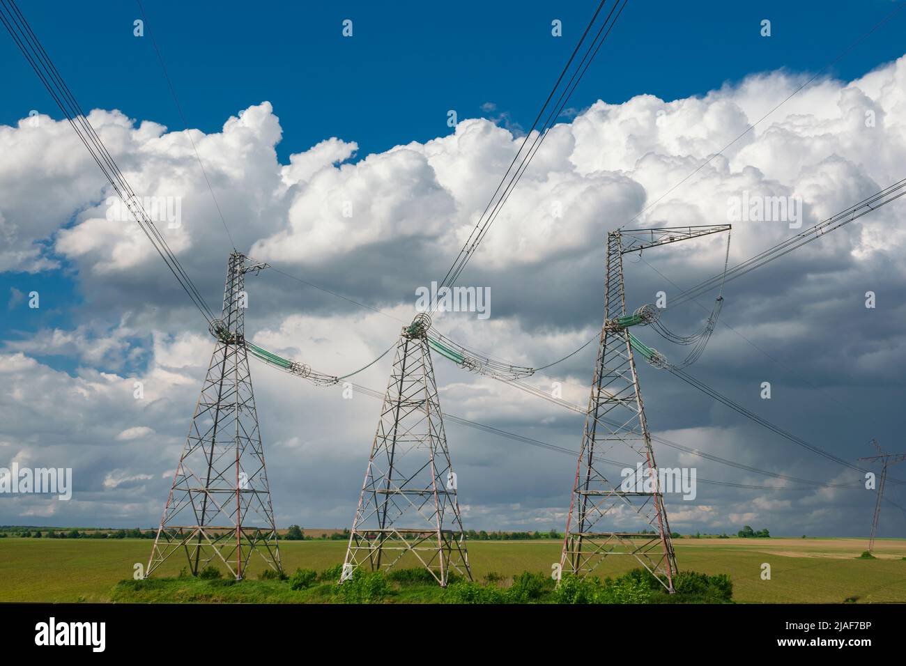 Linea di alimentazione ad alta tensione piloni contro il cielo blu con nuvole. Fornitura e distribuzione di energia elettrica Foto Stock