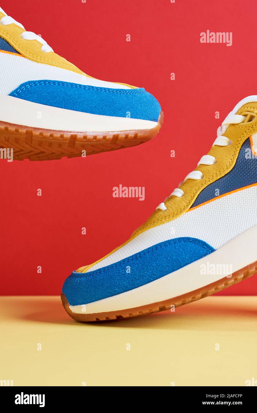 Sneaker volanti alla moda su sfondo creativo e colorato, elegante concetto di minimalismo alla moda, scarpe da levitazione Foto Stock
