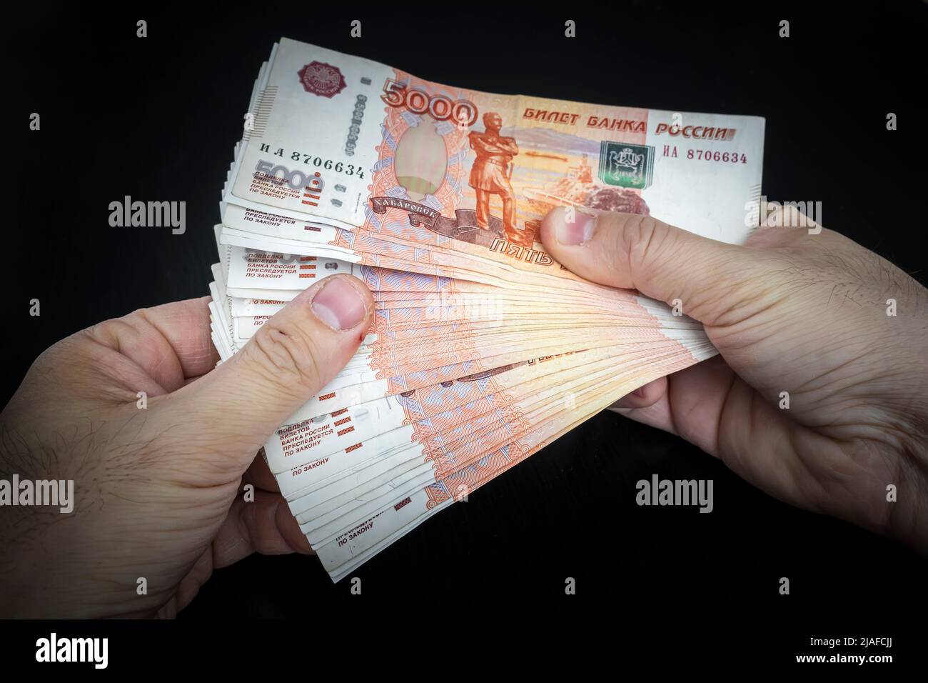 La mano maschio tiene una pila spessa di soldi di contanti. Milioni di rubli russi. Concetto di ricchezza, profitti, affari e finanza. Divieto di cinque millesimi bollette Foto Stock