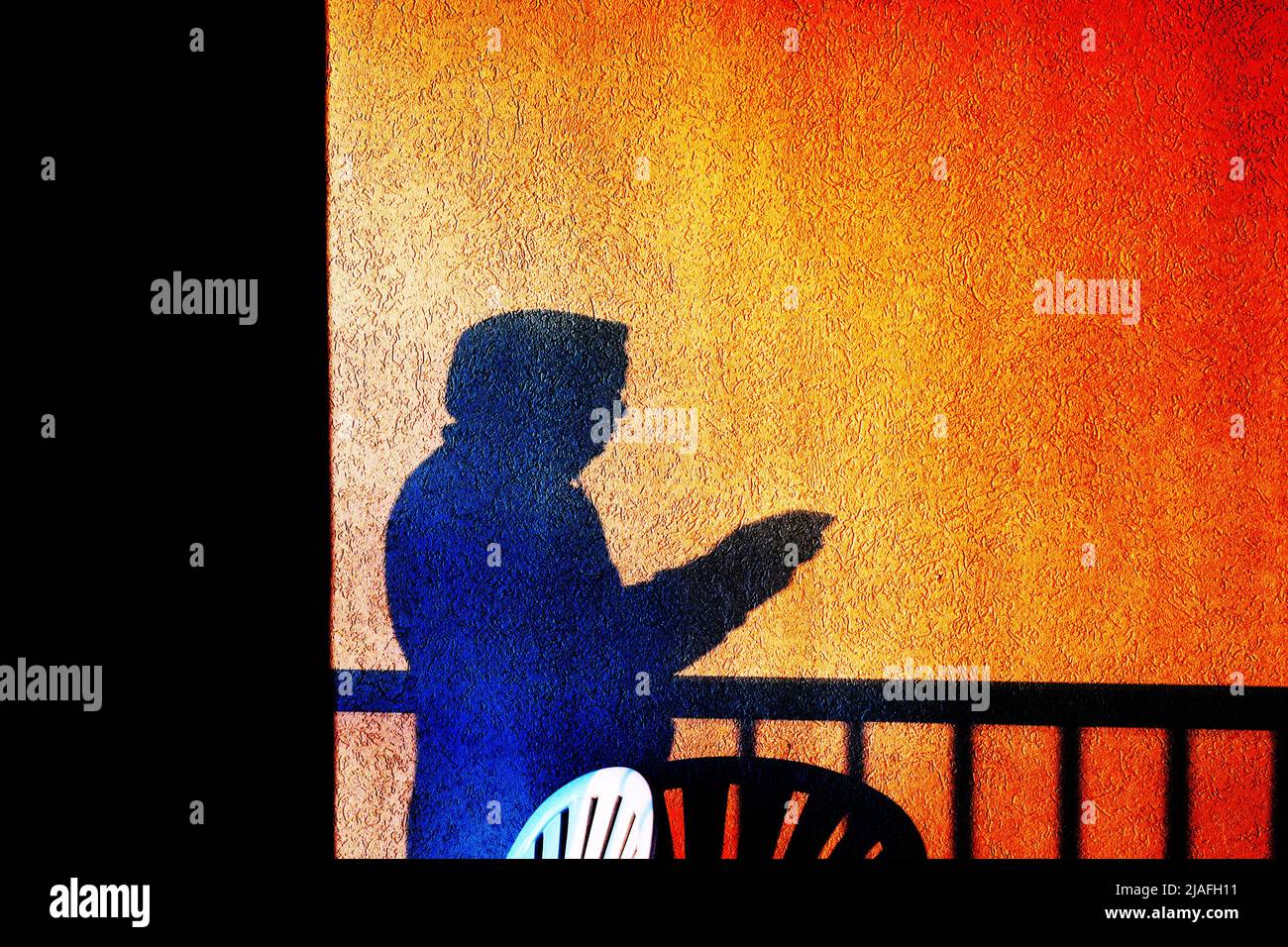 DOBBELGANGER:l'ombra di Un uomo si separa da sé invertita nel tempo e nella coscienza per un selfie di una vista balcone alba. Foto Stock