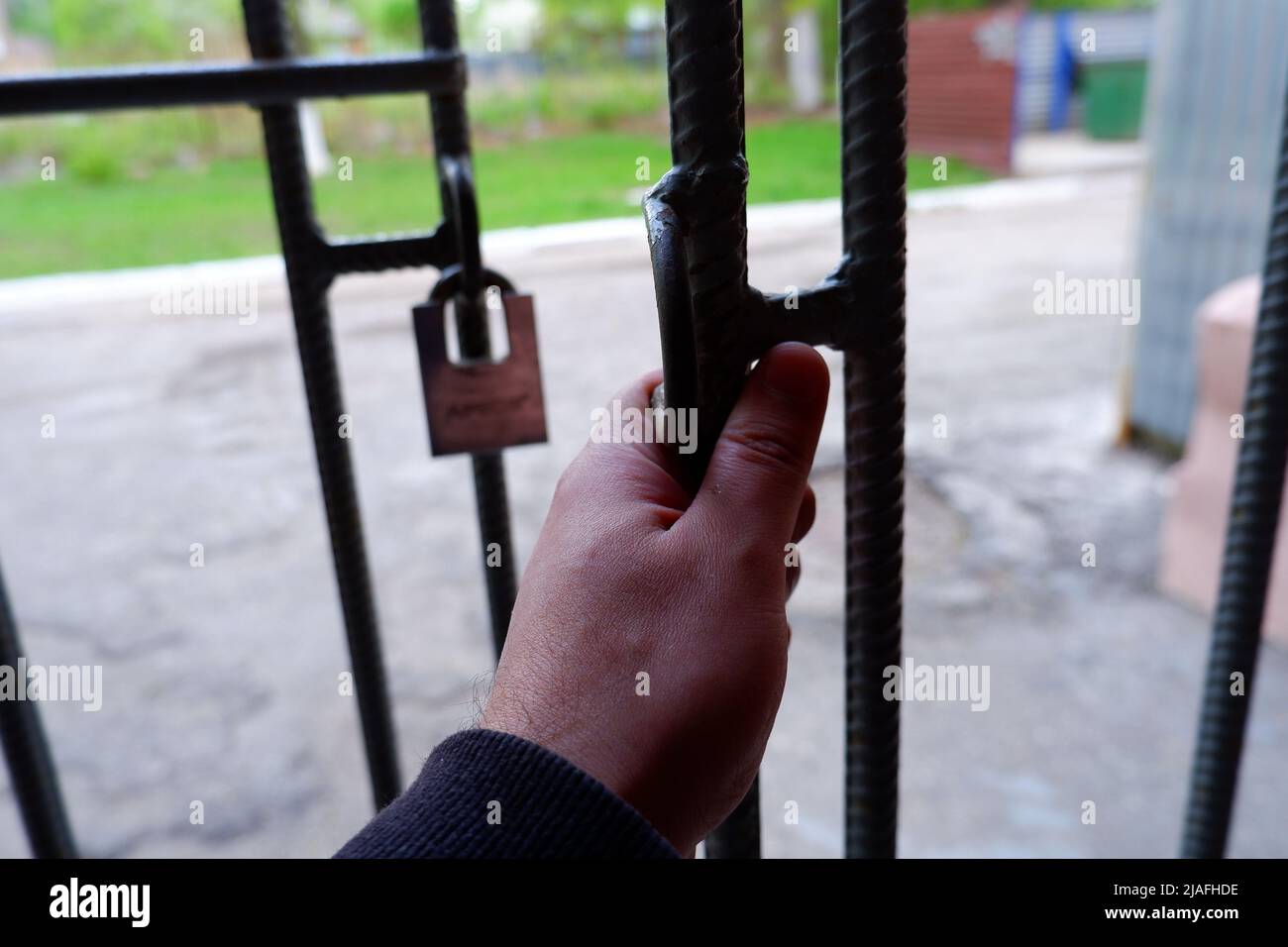 La mano apre il cancello di metallo. Vista in prima persona Foto Stock