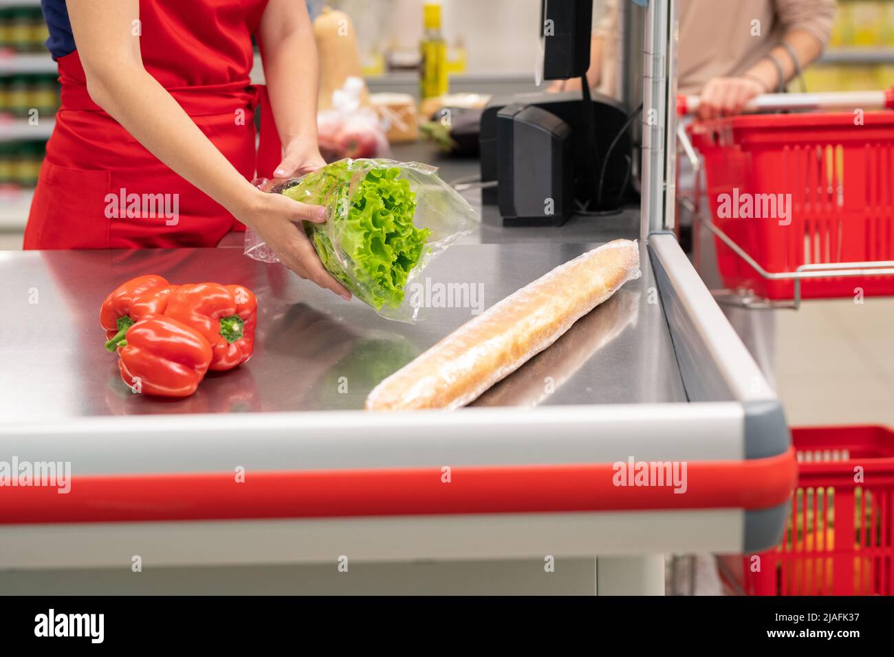 Donna irriconoscibile che acquista alimenti nel moderno supermercato, cassiere li emette un segnale acustico Foto Stock