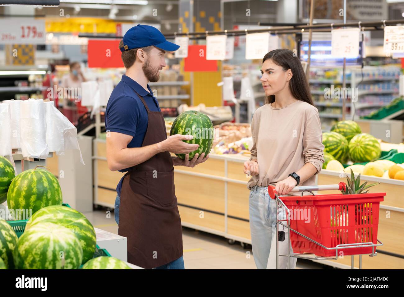 Irriconoscibile operaio del supermercato che indossa uniforme che stabilisce i cocomeri freschi, spazio di copia Foto Stock