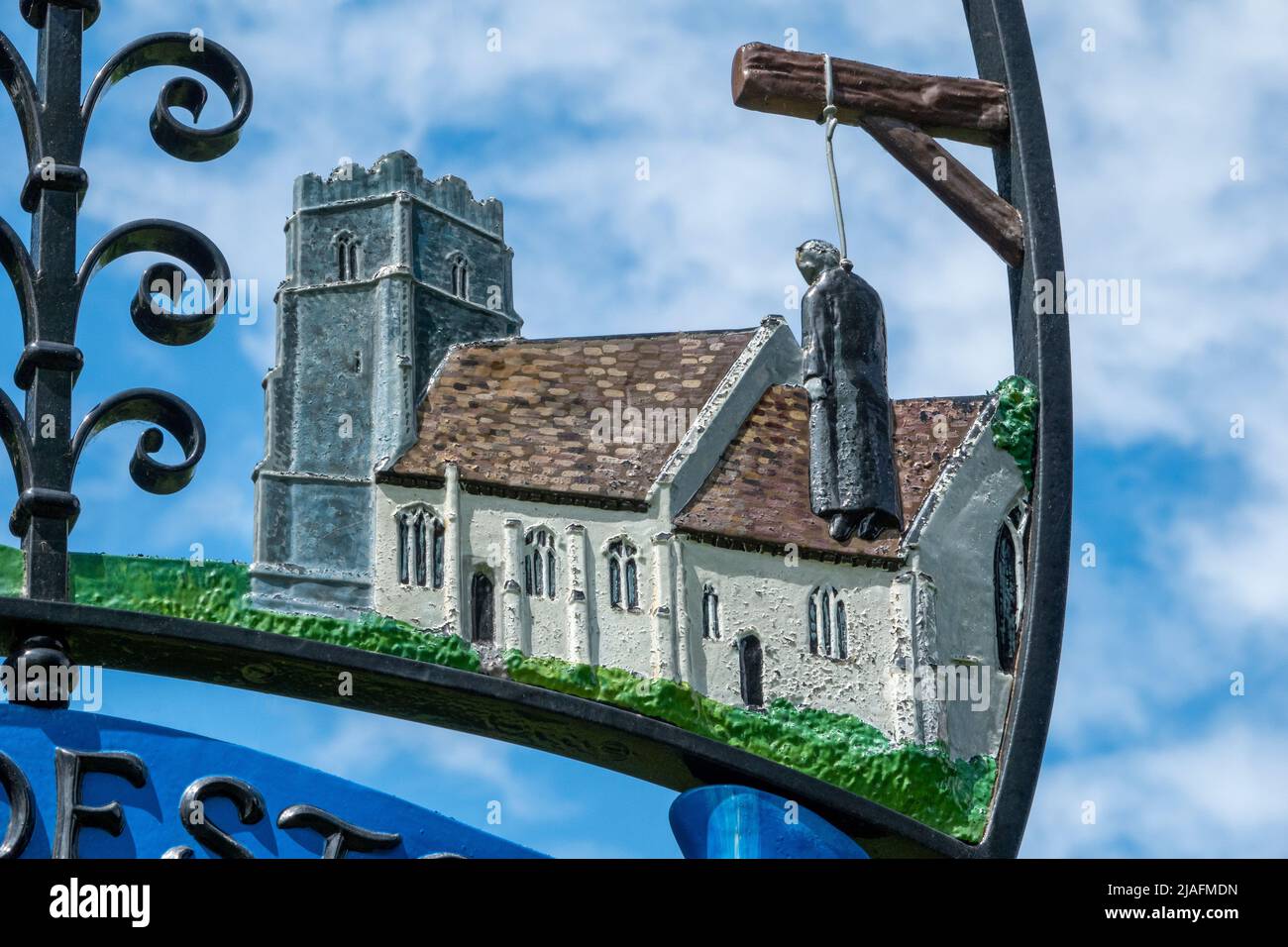 Brandeston villaggio segno contro fogliame e cielo leggermente nuvoloso blu Foto Stock