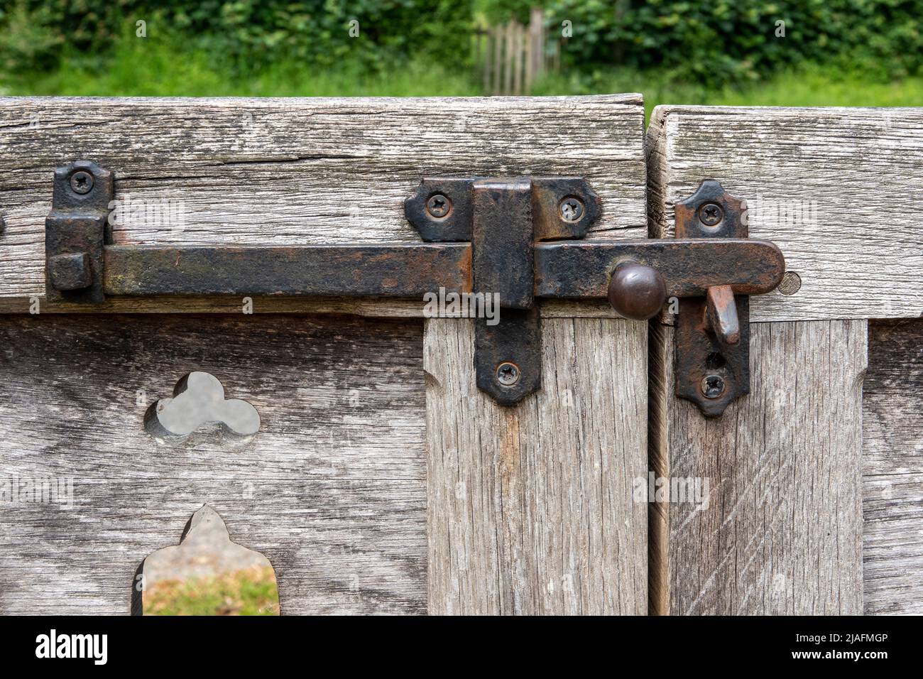 Chiavistello in ferro su cancelli in legno sbiaditi e in difficoltà Foto Stock