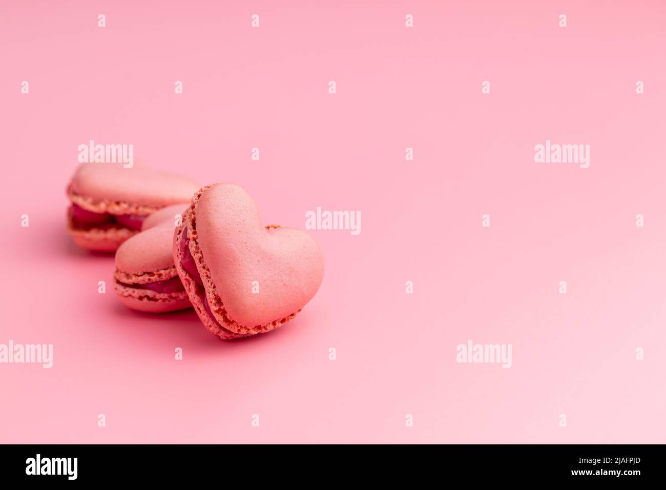 A forma di cuore Dolce macaron su sfondo rosa. Foto Stock