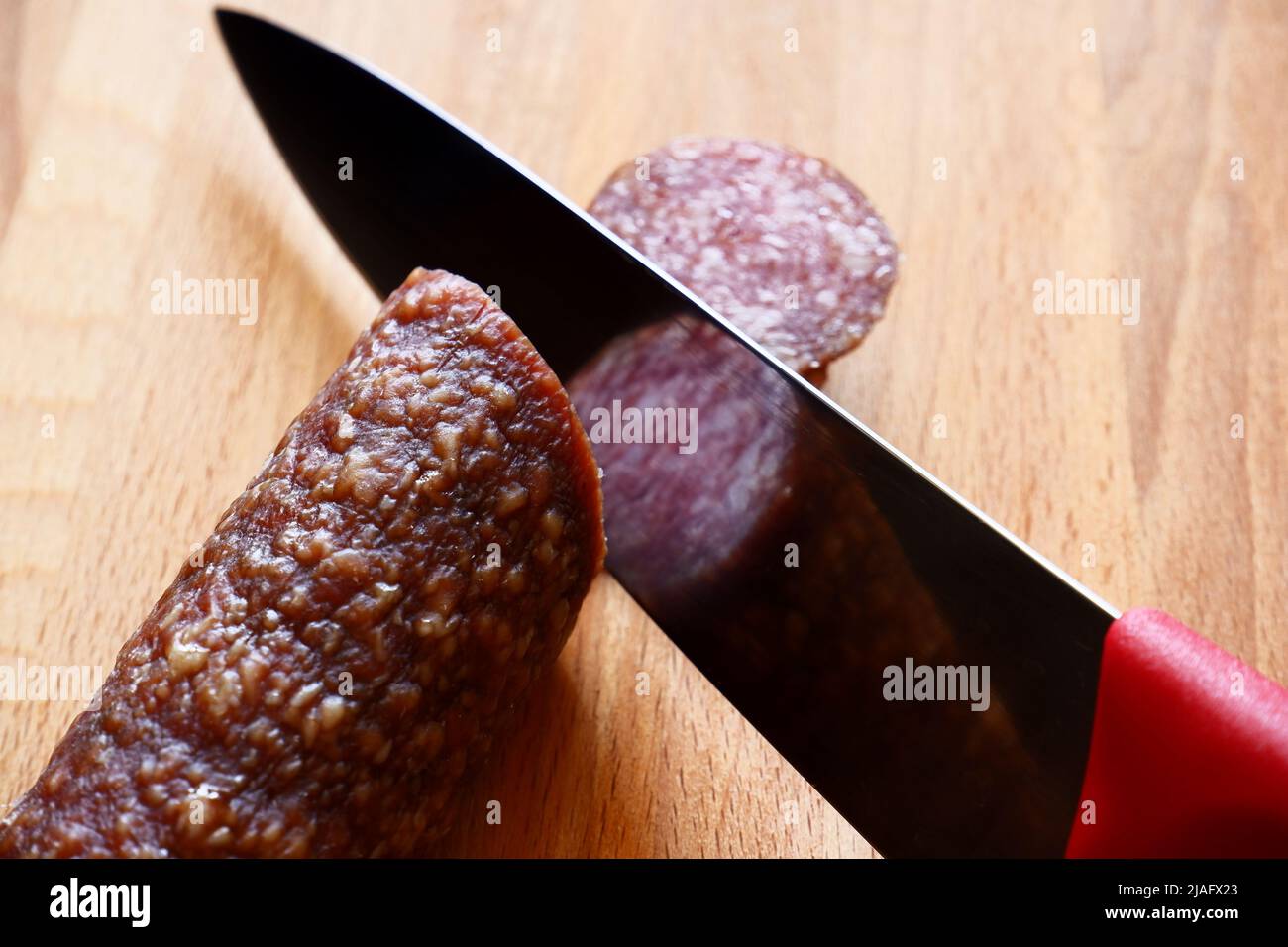 Il coltello taglia il salame su un asse di legno Foto stock - Alamy