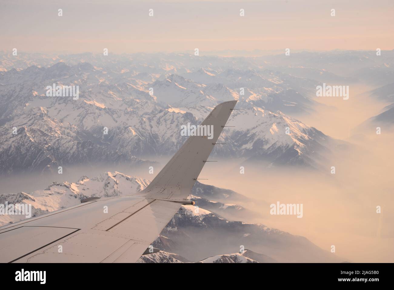 Vista da un aeroplano con ala e montagne nebbia con cime innevate Foto Stock