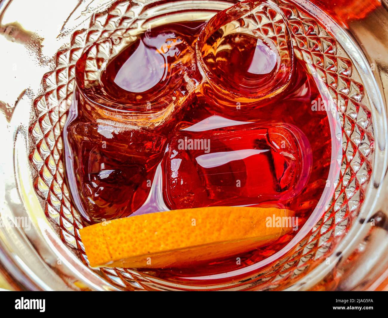 Vista dall'alto di un cocktail rosso con ghiaccio e fetta di arancia in un bicchiere di vetro. Primo piano di cocktail Negroni, Spritz o Americano Foto Stock