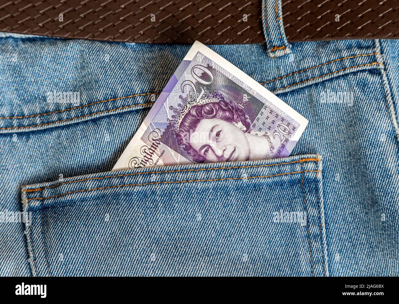 Banconota da venti sterline inglesi che si stacca dalla tasca blu dei jeans Foto Stock