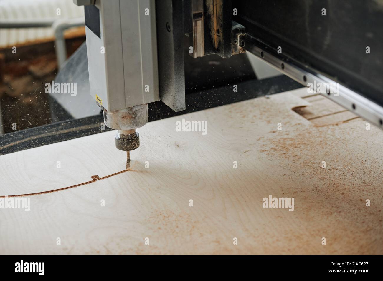 Primo piano della macchina CNC per il taglio del legno in officina di produzione automatizzata con scaglie di segatura in aria, spazio copia Foto Stock