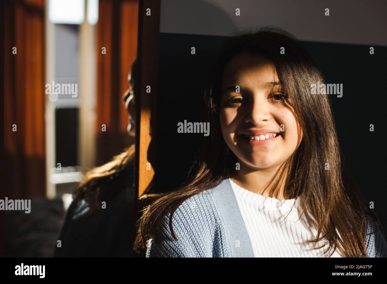 Ritratto di ragazza felice con la luce del sole sul viso a casa Foto Stock