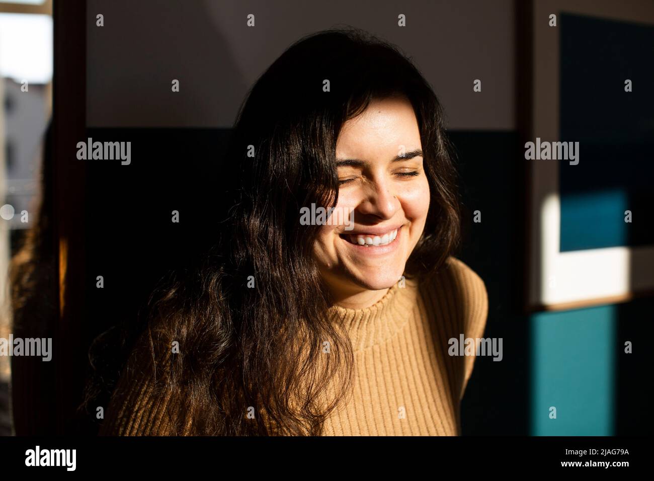 Giovane donna felice con gli occhi chiusi godendo la luce del sole a casa Foto Stock