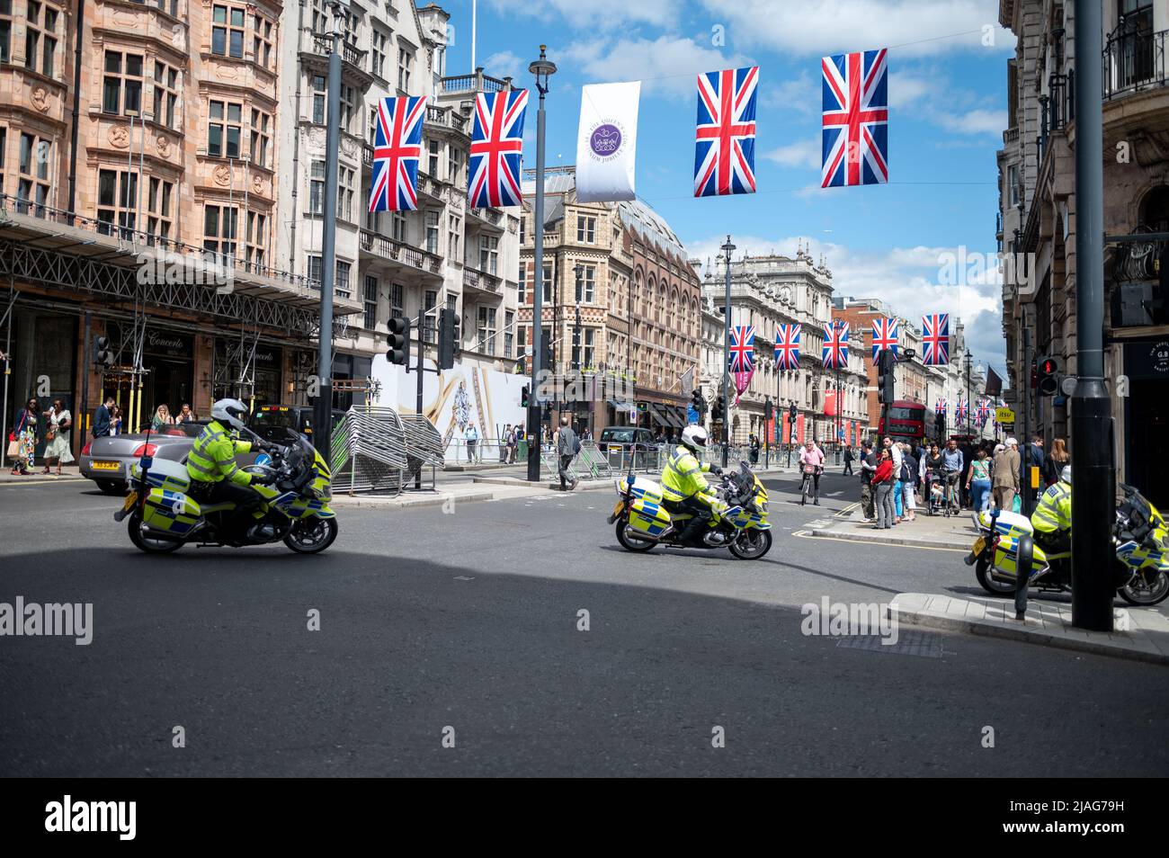 Motociclette di polizia al giubileo di Londra 2022 con bandiere unioni jack sopra la strada iconica giorno di sole Foto Stock