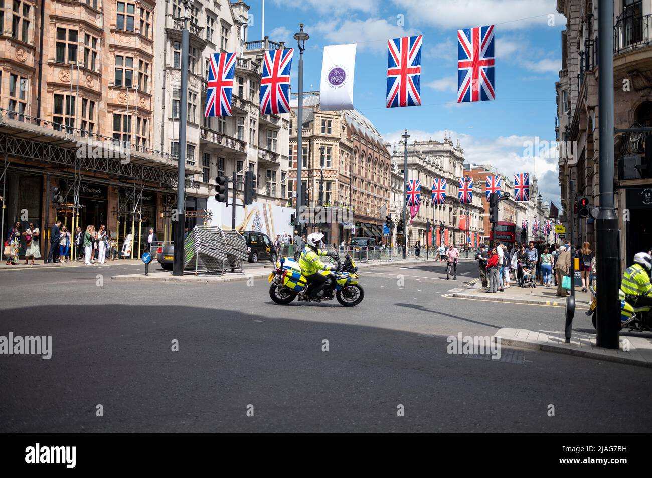 Motociclette di polizia al giubileo di Londra 2022 con bandiere unioni jack sopra la strada iconica giorno di sole Foto Stock