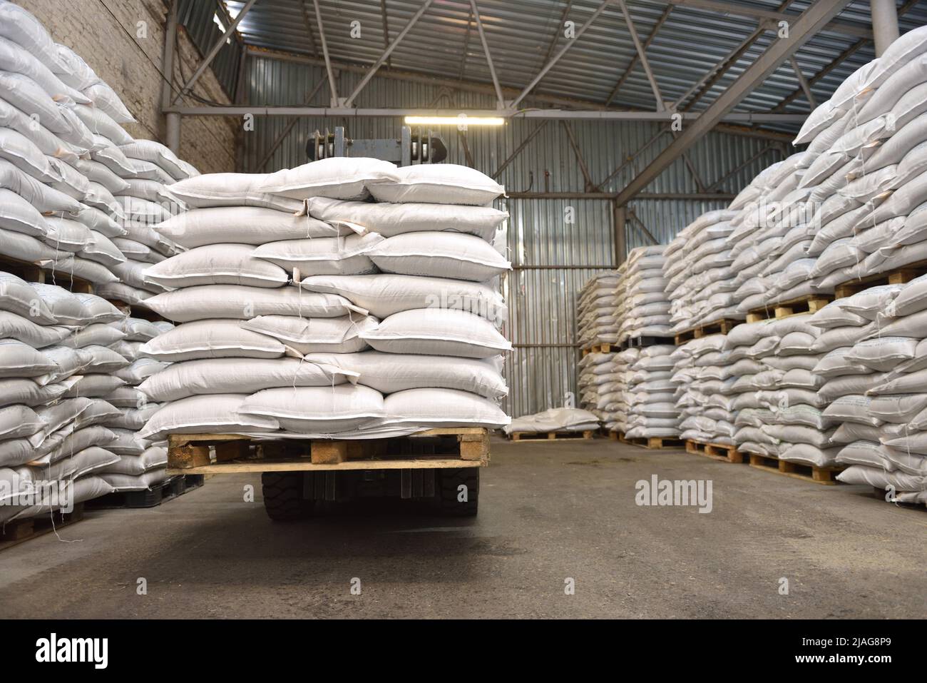 Sacchi di grano impilati bianchi in un magazzino Foto Stock