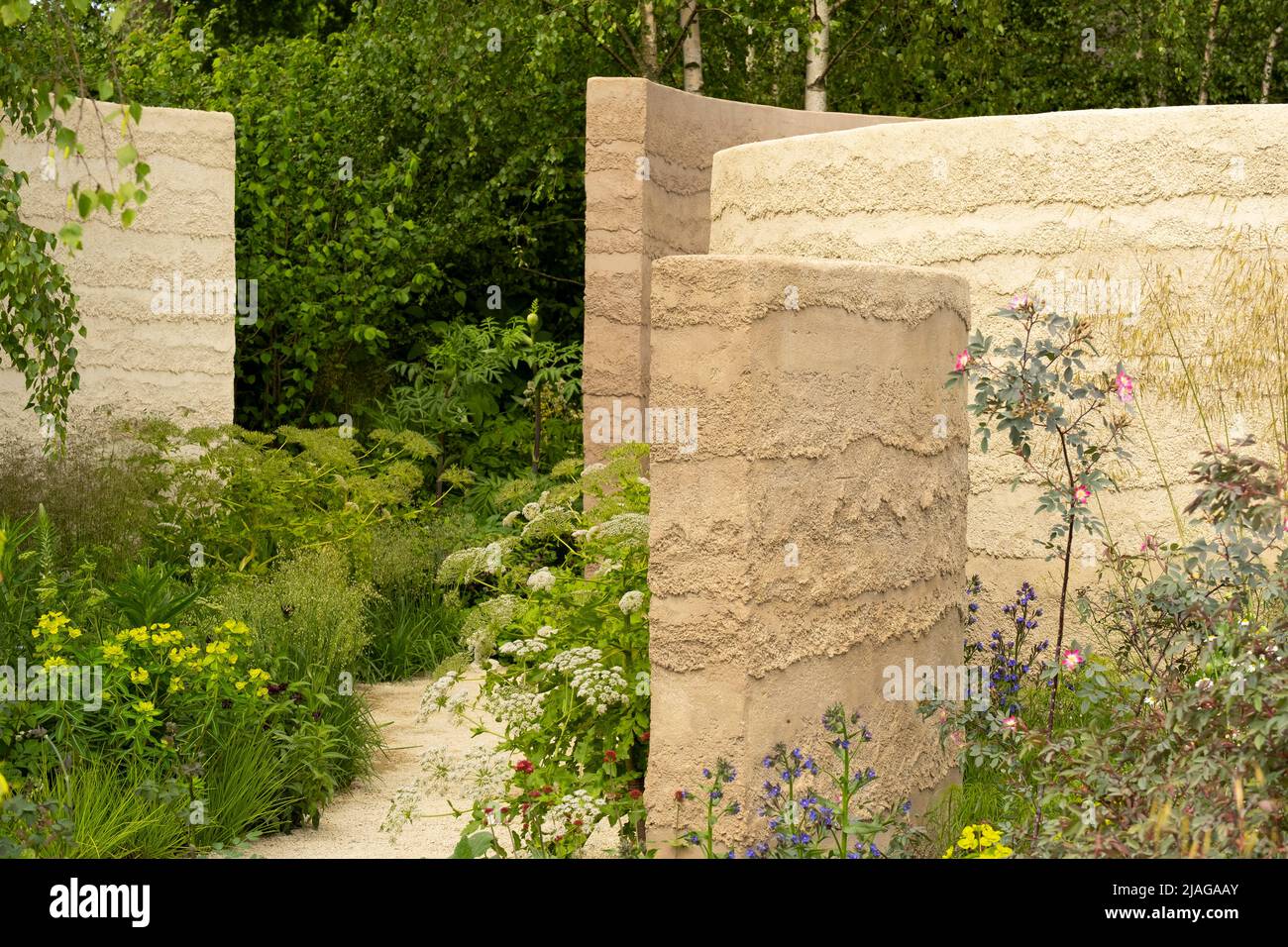 Pareti curve in argilla circondate da erbacee perenni e alberi nel giardino mentale progettato da Andy Sturgeon Foto Stock