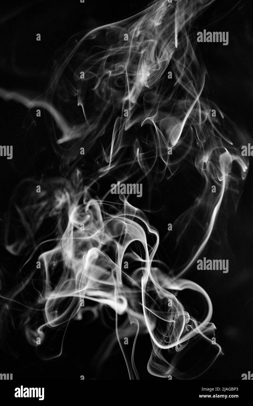 Un modello di fumo bianco, vorticoso, ascendente su uno sfondo nero, la foto potrebbe essere usata come sfondo, trama di fumo o astratto, o pho di stock generale Foto Stock