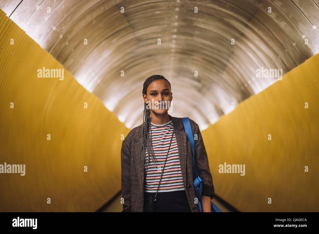 Ritratto di giovane donna sorridente con capelli intrecciati in piedi nel tunnel della metropolitana Foto Stock