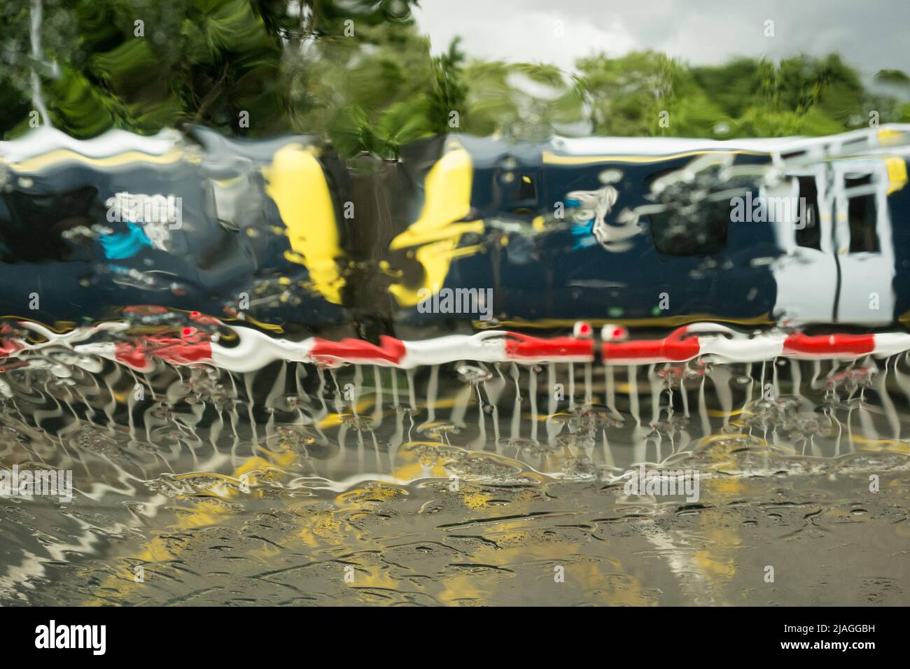 Un treno sud-occidentale che attraversa il livello Vine Road di Network Rail attraversando le barriere in caso di pioggia battente, Barnes, Londra sud-occidentale, Inghilterra, Regno Unito Foto Stock