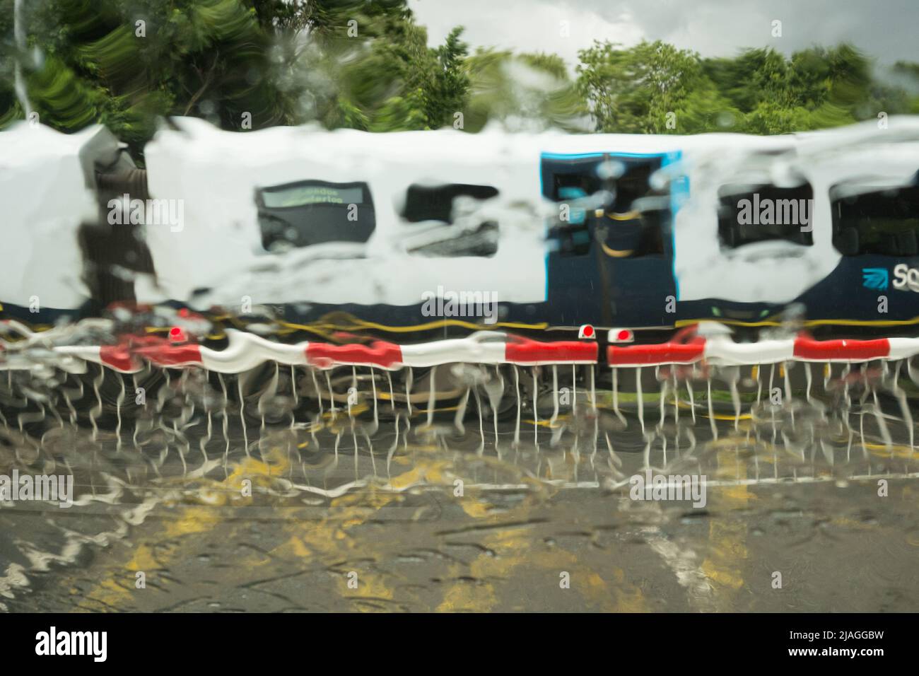Un treno sud-occidentale che attraversa il livello Vine Road di Network Rail attraversando le barriere in caso di pioggia battente, Barnes, Londra sud-occidentale, Inghilterra, Regno Unito Foto Stock