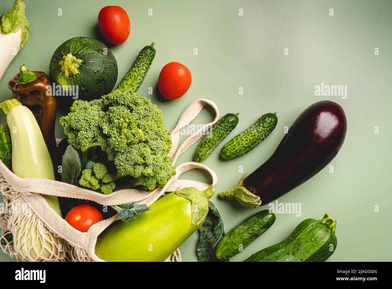 Borsa a rete ecologica con verdure biologiche verdi su sfondo verde. Disposizione piatta, vista dall'alto. Concetto senza rifiuti, senza plastica. Dieta sana, pulita e disintossicante Foto Stock