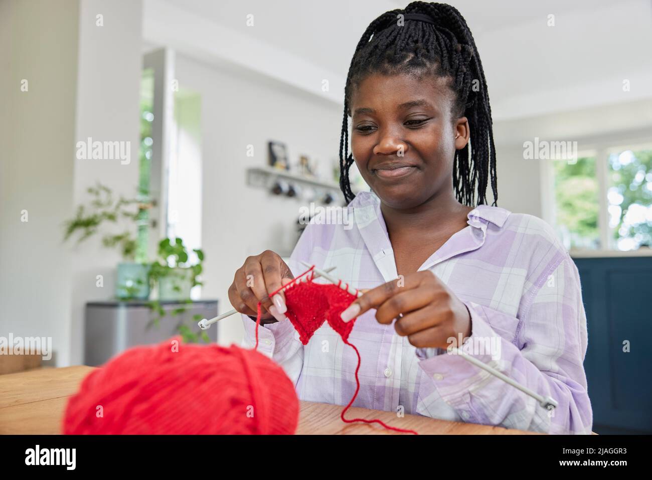 Ragazza adolescente con maglia di lana sul tavolo a casa Foto Stock