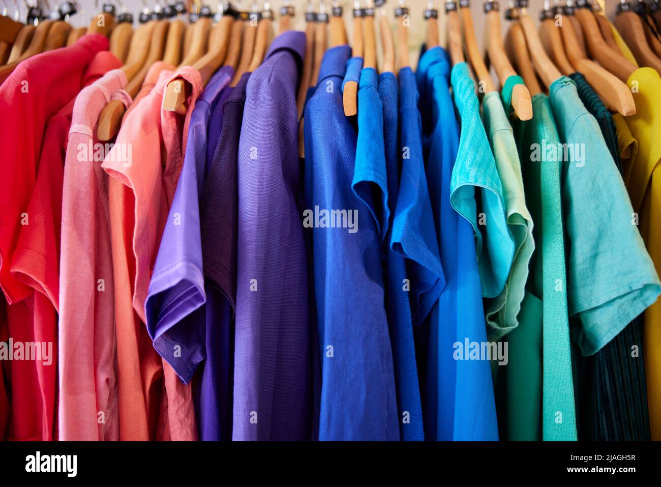 Abbigliamento colorato sostenibile Hanging on Rail in Charity o Thrift Store vendere la moda sostenibile Foto Stock