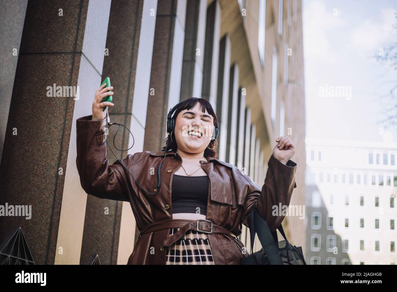 Felice giovane donna con occhi chiusi ballare mentre si ascolta la musica attraverso le cuffie Foto Stock