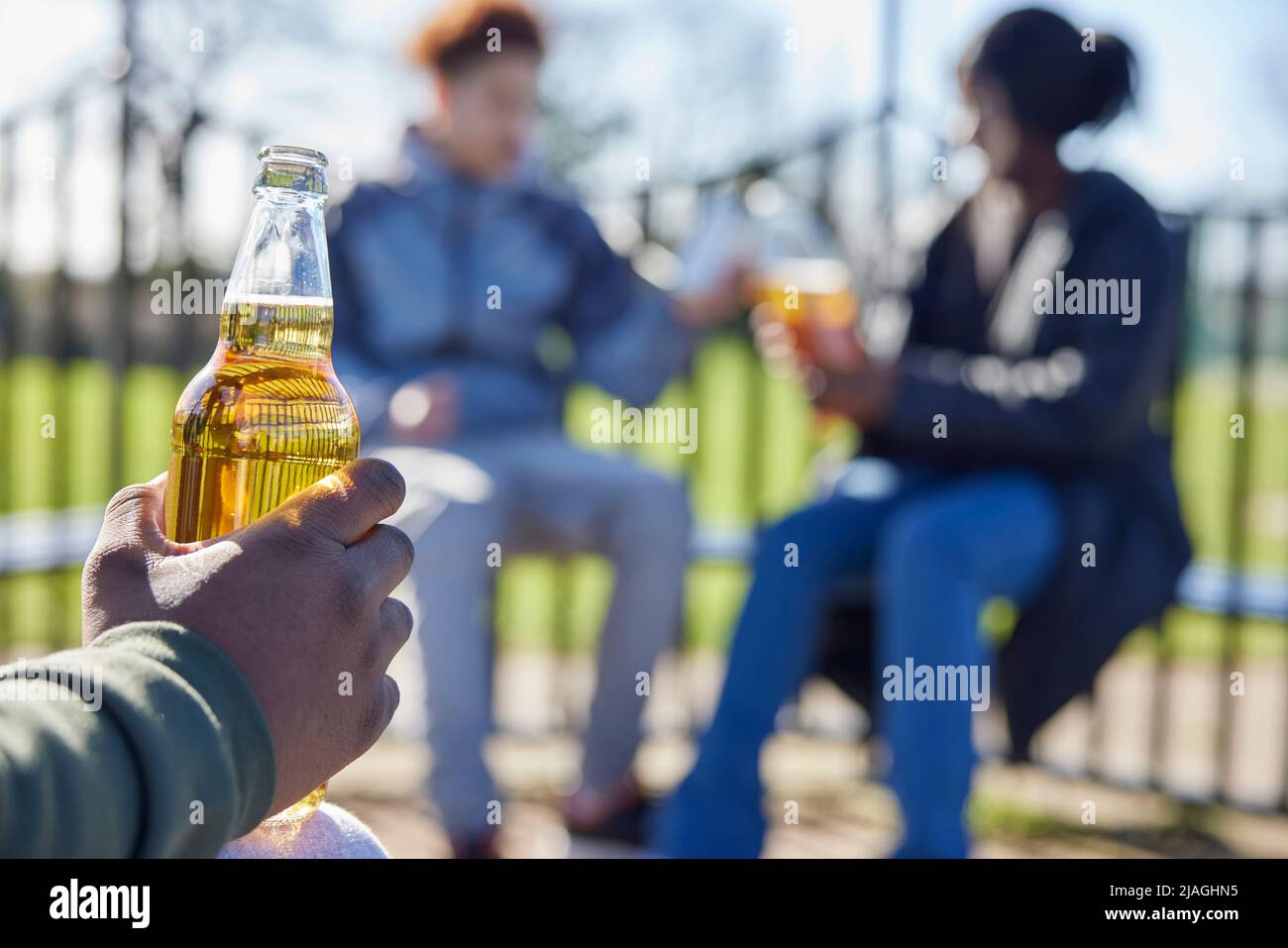 Primo piano di adolescenti minorenni che bevono alcol nel Parco Foto Stock